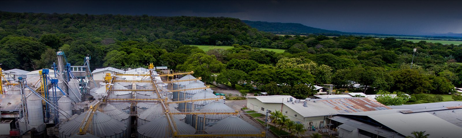 Paisaje agrícola con instalaciones industriales y montañas al fondo
